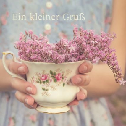 Rosa Blüten in einer Tasse mit kleinem Gruss